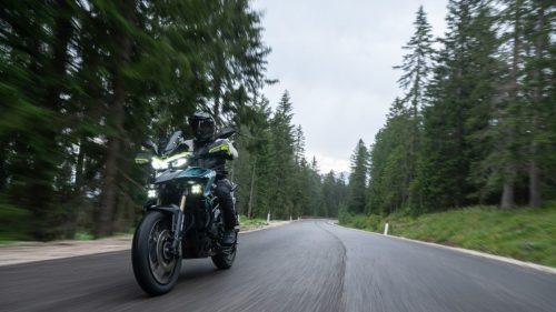 Benelli TRK 902 Xplorer (2026) – Fahraufnahme frontal auf kurviger Waldstrasse mit eingeschaltetem LED-Scheinwerfer