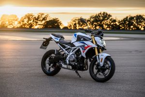BMW F 450 R 2027 – M Sport in Snaefell Weiß / M Motorsport, Standaufnahme schräg von vorn rechts bei Sonnenuntergang