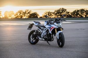 BMW F 450 R 2027 – M Sport in Snaefell Weiß / M Motorsport, Standaufnahme schräg von vorn rechts im Gegenlicht der Abendsonne
