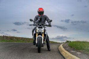 BMW F 450 R 2027 – M Sport in Snaefell Weiß / M Motorsport, Frontansicht mit Fahrer in grauer Jacke und rotem Helm, der hinter dem Motorrad steht