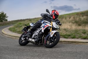 BMW F 450 R 2027 – M Sport in Snaefell Weiß / M Motorsport in Schräglage in einer Linkskurve, Frontansicht mit goldener Upside-down-Gabel