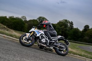 BMW F 450 R 2027 – M Sport in Snaefell Weiß / M Motorsport in Schräglage am Kurvenausgang mit Blick auf Reihenzweizylinder und Underfloor-Auspuff