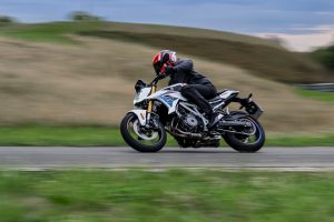 BMW F 450 R 2027 – M Sport in Snaefell Weiß / M Motorsport, Fahraufnahme von rechts mit Mitzieheffekt vor Grashang