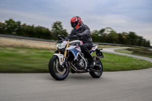BMW F 450 R 2027 – M Sport in Snaefell Weiß / M Motorsport, Fahraufnahme frontal mit LED-Scheinwerfer und goldener Gabel