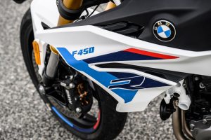 BMW F 450 R 2027 – Detailansicht der Seitenverkleidung mit stilisiertem R, F-450-Schriftzug und BMW-Logo in Snaefell Weiß / M Motorsport