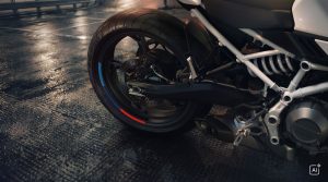 BMW F 450 R 2027 – Detailansicht des Hinterrads mit Felgenrandaufkleber in M-Farben auf nassem Asphalt (KI-generiertes BMW-Pressebild)