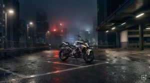 BMW F 450 R 2027 – M Sport in Snaefell Weiß / M Motorsport auf einem nassen Parkplatz vor Hochhäusern bei Nacht (KI-generiertes BMW-Pressebild)