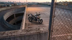 BMW F 450 R 2027 – M Sport in Snaefell Weiß / M Motorsport auf einem Parkdeck neben einer Rampe in der Abenddämmerung (KI-generiertes BMW-Pressebild)