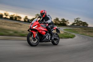 BMW F 450 RR 2027 – Sport in Racing Red in Schräglage auf der Rennstrecke, Fahrer mit rot-schwarzem Helm und weiß-grauer Lederkombi