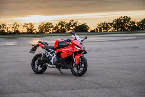 BMW F 450 RR 2027 – Sport in Racing Red, Standaufnahme seitlich von vorn auf großer Asphaltfläche im Abendlicht
