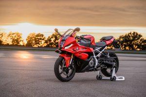 BMW F 450 RR 2027 – Sport in Racing Red auf weißem Montageständer, Standaufnahme schräg von vorn bei Sonnenuntergang