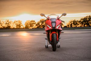 BMW F 450 RR 2027 – Sport in Racing Red auf Montageständer, Frontansicht mit LED-Scheinwerfer und Splitface vor der Abendsonne