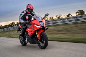 BMW F 450 RR 2027 – Sport in Racing Red in Fahrt, Nahaufnahme von vorn mit Fahrer hinter dem Windschild