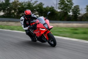 BMW F 450 RR 2027 – Sport in Racing Red in tiefer Schräglage durch eine Kurve, Fahrer mit ausgestelltem Knie