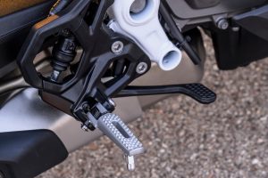 BMW F 450 RR 2027 – Sport in Racing Red, Detailaufnahme der Fahrerfußraste mit Schalthebel und Fersenschutz