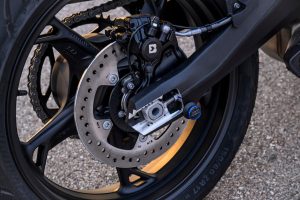 BMW F 450 RR 2027 – Sport in Racing Red, Detailaufnahme des Hinterrads mit Bremsscheibe, Kettenspanner und Aluminiumschwinge