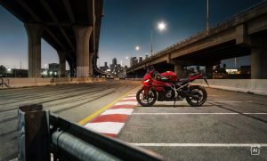BMW F 450 RR 2027 – Sport in Racing Red an rot-weißen Curbs unter einer Hochstraße in der Dämmerung (KI-generiertes BMW-Pressebild)