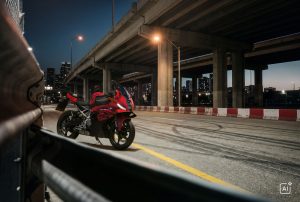 BMW F 450 RR 2027 – Sport in Racing Red hinter einer Leitplanke unter einer Hochstraße bei Nacht (KI-generiertes BMW-Pressebild)