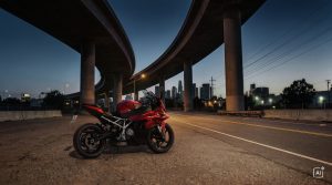BMW F 450 RR 2027 – Sport in Racing Red unter geschwungenen Hochstraßen vor der Skyline (KI-generiertes BMW-Pressebild)