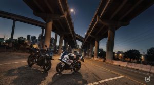 BMW F 450 RR 2027 – F 450 RR in Schwarz und Weiß nebeneinander unter Hochstraßen in der Dämmerung (KI-generiertes BMW-Pressebild)