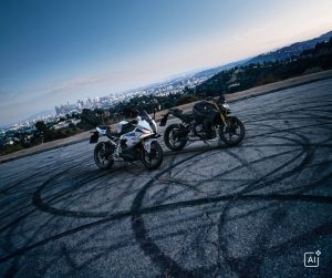 BMW F 450 RR 2027 – F 450 RR M Sport neben einer schwarzen F 450 R auf einem Aussichtsplatz über der Stadt (KI-generiertes BMW-Pressebild)