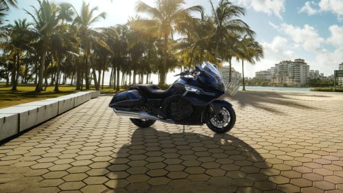 BMW K 1600 Bagger 2027 Edition II in Imperialblau metallic auf einer Uferpromenade unter Palmen