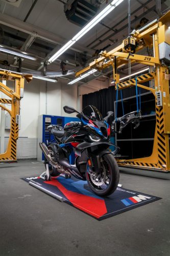 BMW M 1000 RR 2027 in M Motorsport Lackierung – Frontansicht auf BMW M Teppich unter Montagekran