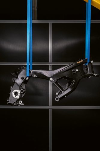 BMW M 1000 RR 2027 – neuer M Motorsport Rahmen der dritten Generation frei hängend an blauen Gurten, Hochformat