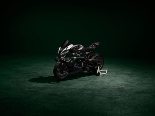 BMW M 1000 RR Limited Edition Isle of Man TT 2026 – Frontansicht schräg links in British Racing Green Uni Matt mit Linkskurven-Grafiken des Mountain Course, dunkles Studio mit grünem Spotlight