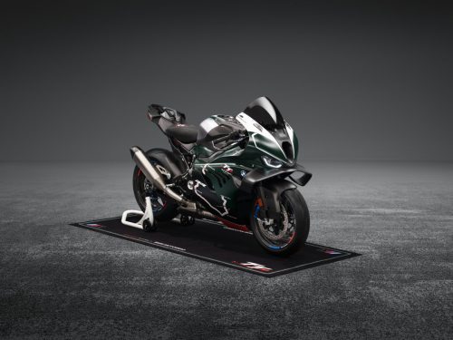 BMW M 1000 RR Limited Edition Isle of Man TT 2026 – Frontansicht schräg rechts auf M Motorradteppich mit TT-Logo, British Racing Green Uni Matt Lackierung und TT-Kurven-Grafiken, grauer Studiohintergrund
