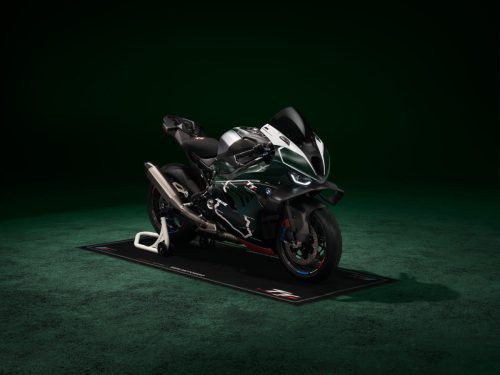 BMW M 1000 RR Limited Edition Isle of Man TT 2026 – Frontansicht schräg rechts auf M Motorradteppich mit TT-Logo, British Racing Green Uni Matt, dunkles Studio mit grünem Spotlight
