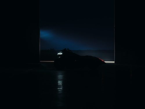 BMW Motorrad Vision K18 – Silhouette im Hangar-Tor bei Nacht mit Scheinwerferlicht und Rücklicht