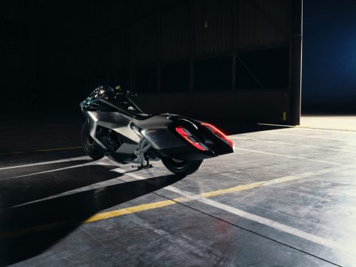 BMW Motorrad Vision K18 – Heckansicht im Hangar mit breitem Carbon-Heck, sechs Endrohren und roter LED-Beleuchtung
