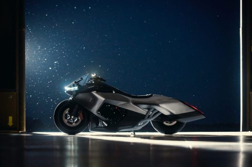 BMW Motorrad Vision K18 – linke Seitenansicht im Hangar mit Staubpartikeln im Gegenlicht und leuchtender LED-Signatur