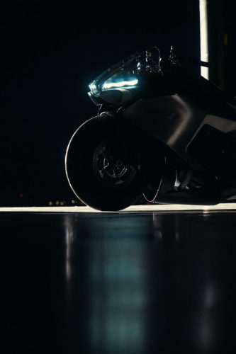 BMW Motorrad Vision K18 – dramatische Froschperspektive von vorne mit Vorderrad und LED-Scheinwerfer im Hangar bei Nacht