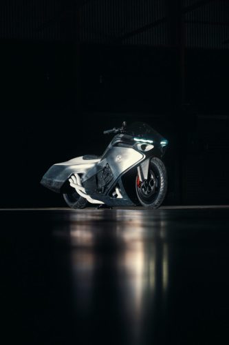 BMW Motorrad Vision K18 – Dreiviertelansicht vorne rechts im Hangar mit BMW Emblem und handgeformter Aluminium-Verkleidung