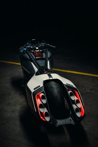 BMW Motorrad Vision K18 – Heckansicht von oben mit sechs Endrohren und rot leuchtenden Rückleuchten auf Rollfeld