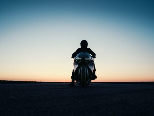 BMW Motorrad Vision K18 – Frontansicht mit Fahrer-Silhouette auf Startbahn bei Sonnenuntergang