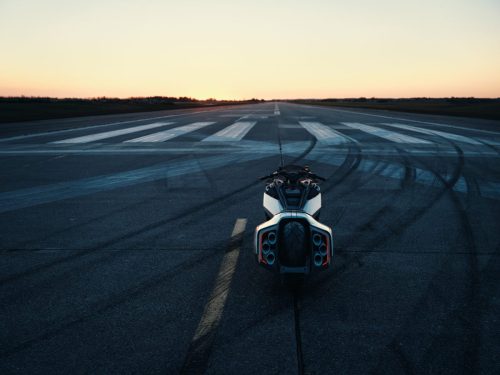 BMW Motorrad Vision K18 – Heckansicht auf Startbahn bei Sonnenuntergang mit Reifenspuren und sechs Endrohren