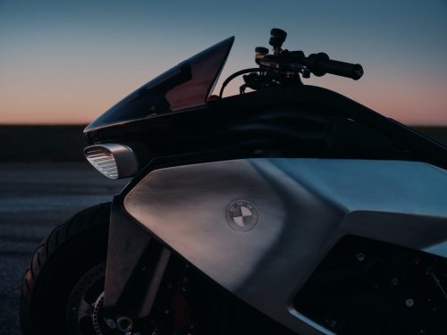 BMW Motorrad Vision K18 – Detailansicht der Windschutzscheibe mit BMW Emblem und geprägtem Aluminium bei Abendsonne