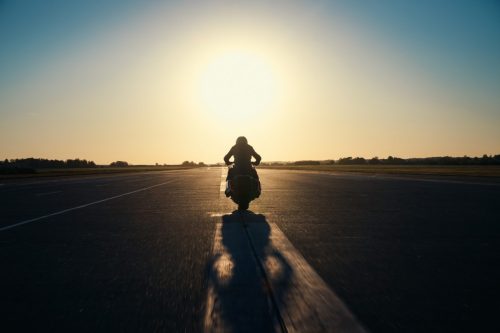 BMW Motorrad Vision K18 – Fahrer fährt im Gegenlicht auf Startbahn mit langem Schatten
