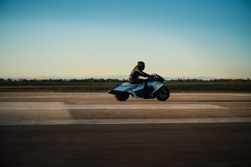 BMW Motorrad Vision K18 – Fahrt auf Startbahn mit Mitzieher-Effekt, Aluminium-Karosserie und Alpenpanorama im Hintergrund