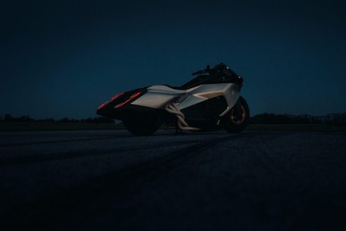 BMW Motorrad Vision K18 – rechte Seitenansicht auf Startbahn bei blauer Stunde mit leuchtenden Rücklichtern und sichtbaren Auspuffkrümmern
