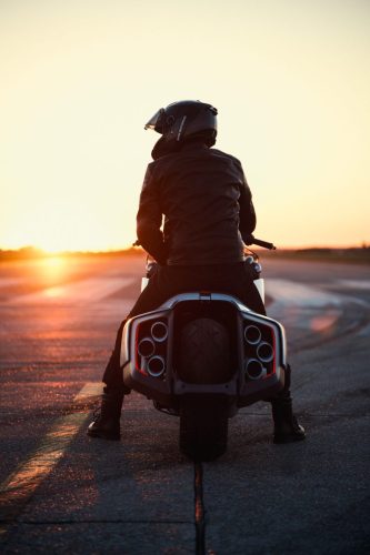 BMW Motorrad Vision K18 – Fahrer-Silhouette von hinten mit sechs Endrohren bei tiefstehender Abendsonne auf Startbahn