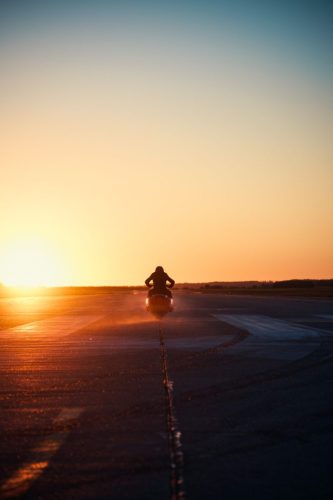 BMW Motorrad Vision K18 – Fahrer fährt auf Startbahn Richtung Sonnenuntergang im Gegenlicht