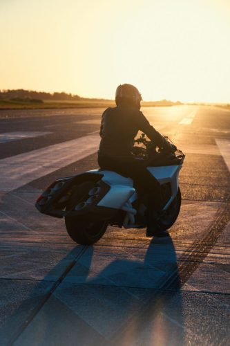 BMW Motorrad Vision K18 – Fahrer steht auf Startbahn im Gegenlicht mit Silhouette und sechs Endrohren
