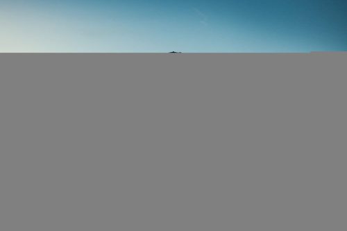 BMW Motorrad Vision K18 – Fahrer auf Startbahn in der Ferne, weite Landschaft mit Aluminium-Karosserie im Sonnenlicht