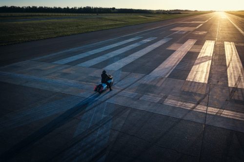 BMW Motorrad Vision K18 – Drohnenaufnahme mit Fahrer auf Startbahn bei Sonnenuntergang und langen Schatten