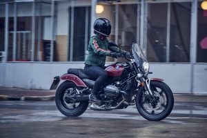 BMW R 12 2025 – Seitenansicht mit Fahrerin in Bewegung, Aventurinrot