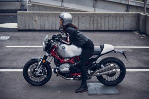 BMW R 12 nineT 2025 – Seitenansicht rechts mit Fahrerin, Aluminium-Silber